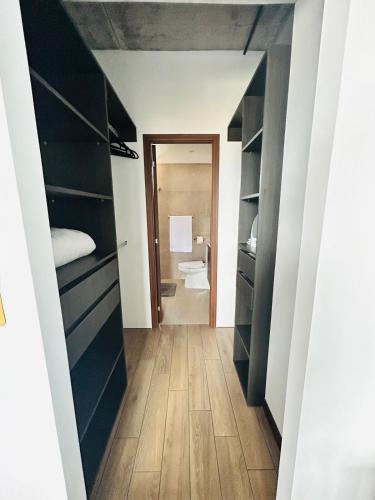 a hallway with black cabinets and a bathroom with a toilet at Cozy Apartment 4 degrees north in Las Victorias