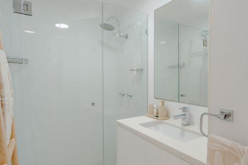 a white bathroom with a sink and a shower at Seacrest 9 in Gold Coast