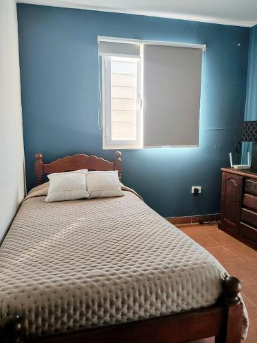 a bedroom with a bed with a blue wall at Kaike in Caleta Olivia