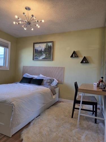 a bedroom with a bed and a table and a chandelier at Room with Shared Bathroom - Stampede & Mountains in Calgary