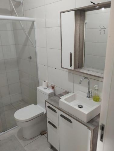 a white bathroom with a toilet and a sink at Chacara Urbana in Navegantes