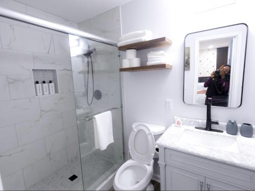 a woman taking a picture of a bathroom with a shower at Comfort Cove Snellville in Snellville