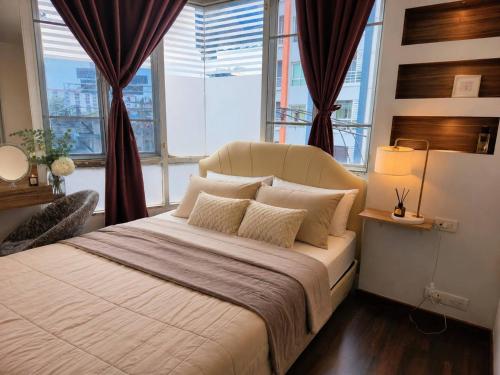 a bedroom with a large bed with two windows at The Greenway Sukhumvit 50 in Phra Khanong