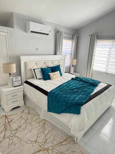a bedroom with a large bed with blue pillows at The Perrys Chateau in Old Harbour