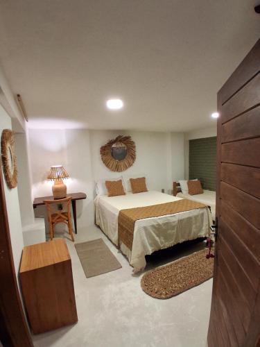 a hotel room with two beds and a table at Casa Irmã Lua in Porto Seguro