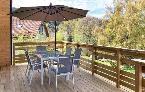 a table and chairs on a deck with an umbrella at Confortable Chalet Moderne in Anould