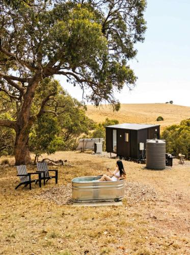a woman sitting in a tub in front of a tree at Gem near the Dam by Tiny Away in Romsey