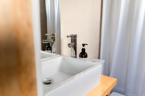 a bathroom with a white sink and a mirror at Hotel Aquaterra in Puerto Natales