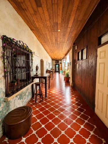 a hallway with a wooden ceiling and a floor with a table at Amura Hostel - Antigua Guatemala in Antigua Guatemala