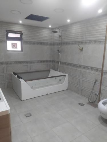 a bathroom with a bath tub and a toilet at فيلا وشاليه فيينا in Al Qasţal