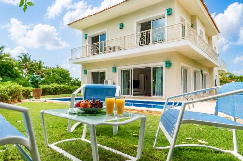 a table and chairs with a bowl of fruit and orange juice at Private Iberosta Villa Lagoon 4BDR- Private Beach and Pool in Punta Cana