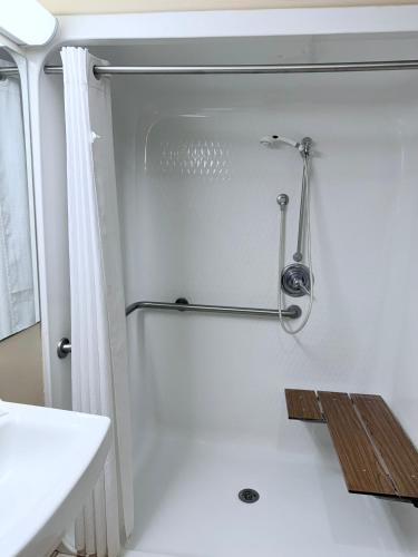 a white bathroom with a shower and a sink at COLLINS INN & SUITES in Collins