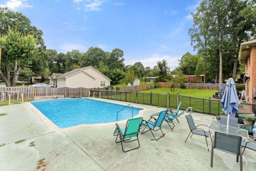 a swimming pool with chairs and a table and a fence at Arden Place - Spacious Retreat with Pool in High Point