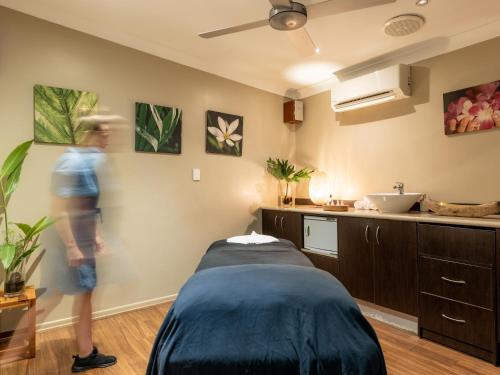 a woman in a room with a bed and a sink at NRMA Angourie Resort, Yamba in Yamba