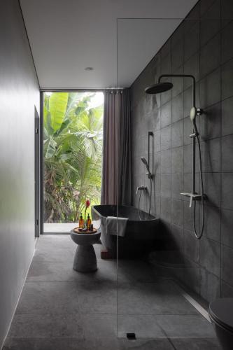 a bathroom with a black tub and a window at UNIT Nuanu Village in Canggu