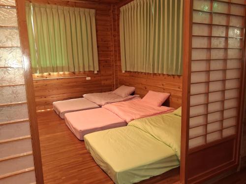 two beds in a room with two windows at Beauty House in Nanzhuang