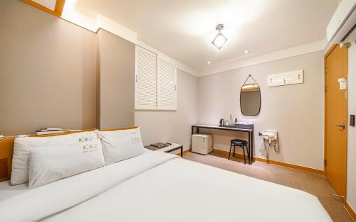 a bedroom with a large white bed and a desk at Osan No25 Hotel in Osan