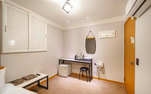 a bedroom with a desk and a bed and a mirror at Osan No25 Hotel in Osan