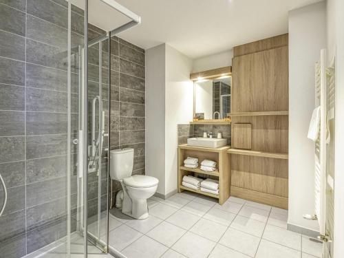 a bathroom with a toilet and a glass shower at Aparthotel Adagio Access Saint Nazaire in Saint-Nazaire
