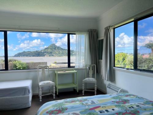 a bedroom with two beds and large windows at Seaview Lodge in Tairua