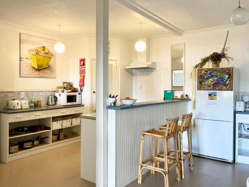 a kitchen with a counter and some stools in it at Seaview Lodge in Tairua