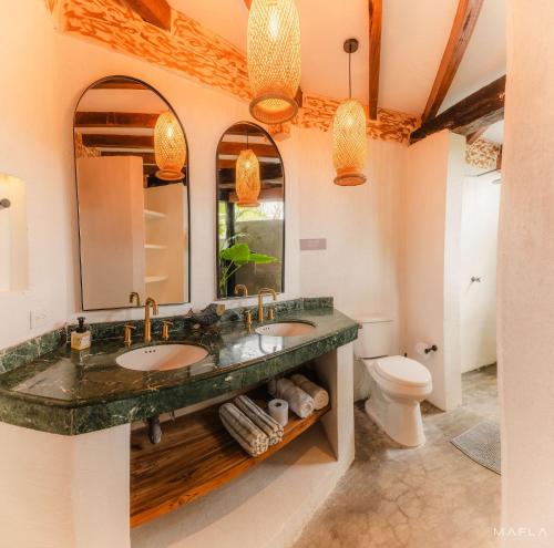 a bathroom with two sinks and a toilet at Ecohotel Raices del Rosario in Cartagena de Indias