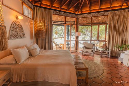 a bedroom with a large bed in a room with windows at Ecohotel Raices del Rosario in Cartagena de Indias