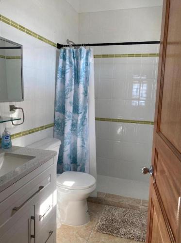a bathroom with a toilet and a shower curtain at Cozy House, Ocean View, Saint Thomas in Contant