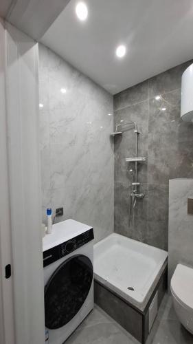 a bathroom with a shower and a washing machine at ЖК Табигат in Borovoye