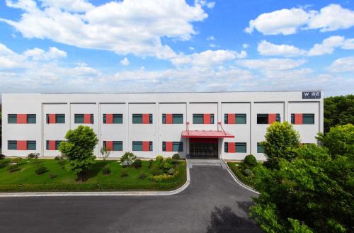 a large white building with red windows and a driveway at W9-Hotel ShangHai PuDong Airport - 24 hours free shuttle bus to Pudong Airport in Shanghai