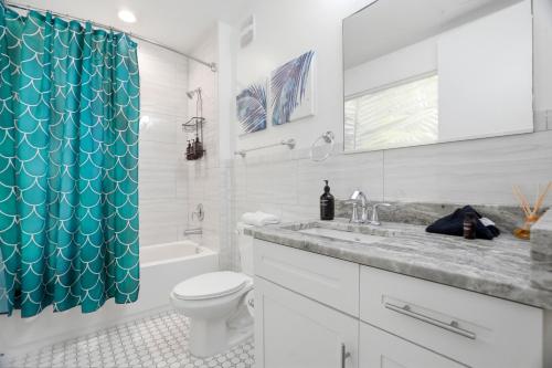 a bathroom with a white toilet and a blue shower curtain at Casa Ybor Apartments on 7th Ave in Tampa