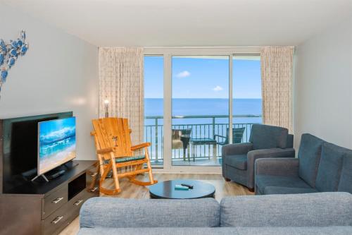 a living room with a couch and a tv and a balcony at Oceanfront Paradise Sleeps 10 w Stunning Sunrises in Myrtle Beach