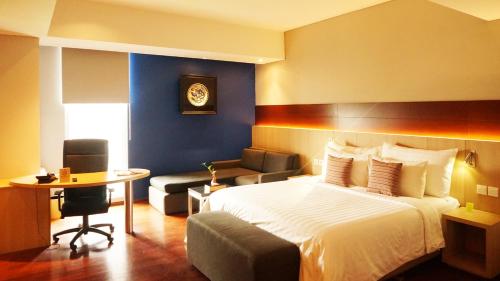 a hotel room with a bed and a chair and a table at Ra Premiere Simatupang in Jakarta