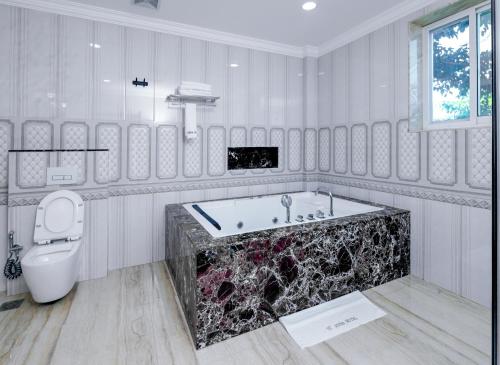 a white bathroom with a tub and a toilet at Fountain Palace Hotel & Suites in Kampala