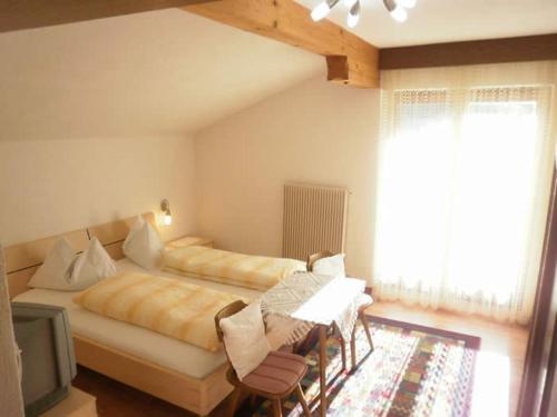a bedroom with a bed and a table and a tv at Pension Tannenhof in Laces
