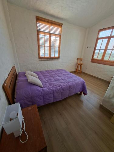 a bedroom with a purple bed and a table at Villa Luna in Chincha
