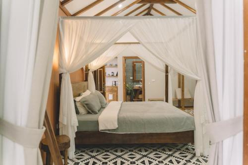 a bedroom with a canopy bed with white curtains at The Wooden Gate in Xuân Sơn