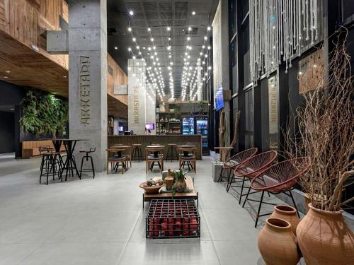 a lobby with chairs and tables and a restaurant at ibis Styles Maceió Pajuçara in Maceió