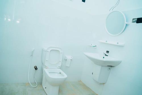 a white bathroom with a toilet and a sink at Grace Inn in Kalkudah