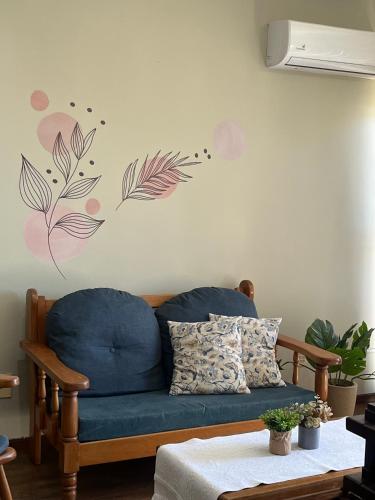 a living room with a blue couch and flowers on the wall at Conforto e simplicidade no centro da cidade in Santana do Livramento