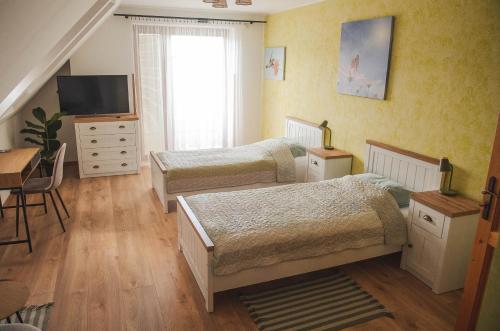 a bedroom with two beds and a desk and a television at Penzion Pod Hradem in Potštejn