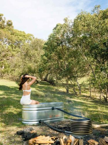 a woman in a white dress sitting in a fire pit at Gem near the Dam by Tiny Away in Romsey
