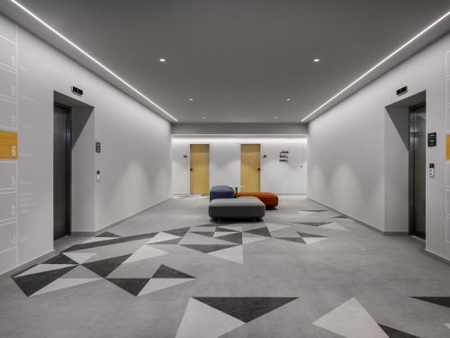 an empty hallway with a chair and a floor with triangles at ibis Budapest Stadium in Budapest