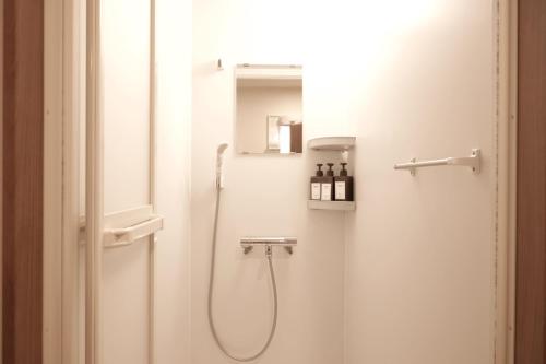 a bathroom with a shower with a sink and a mirror at 66 Lodge Country Station in Kimobetsu