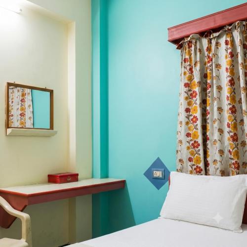 a bedroom with a bed and a window with a mirror at Sri Ganapathy Lodge in Coimbatore