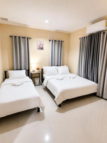 two beds in a hotel room with curtains at Block 23 - Dogwood in Bacolod