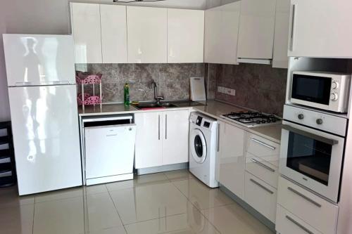a kitchen with white cabinets and a washer and dryer at Caesar resort 2 bedrooms Cornelius in Vrysoules