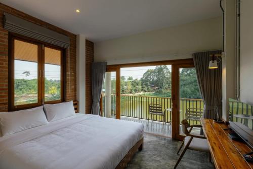 a bedroom with a bed and a balcony with windows at Glai boutique hotel in Ban Cha Prong