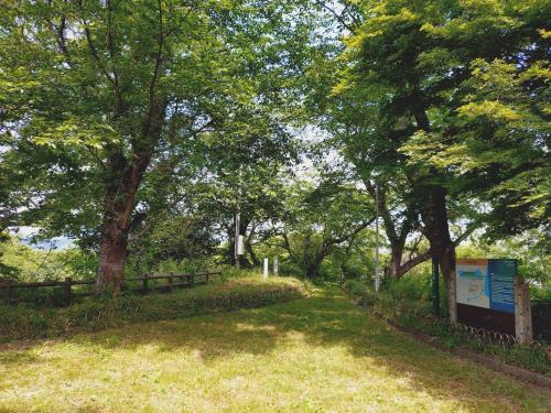 a path in a park with trees and a sign at Guest House NODOKA in Toyooka