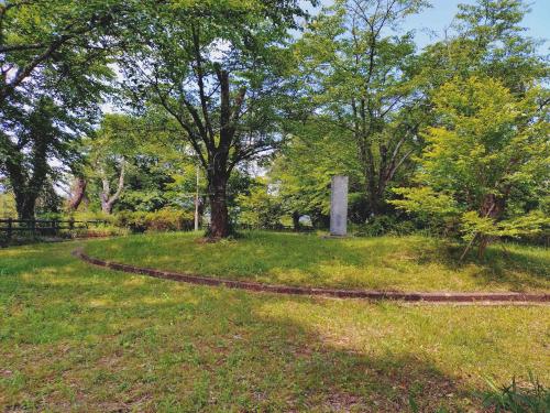 a path in a park with trees and a monument at Guest House NODOKA in Toyooka